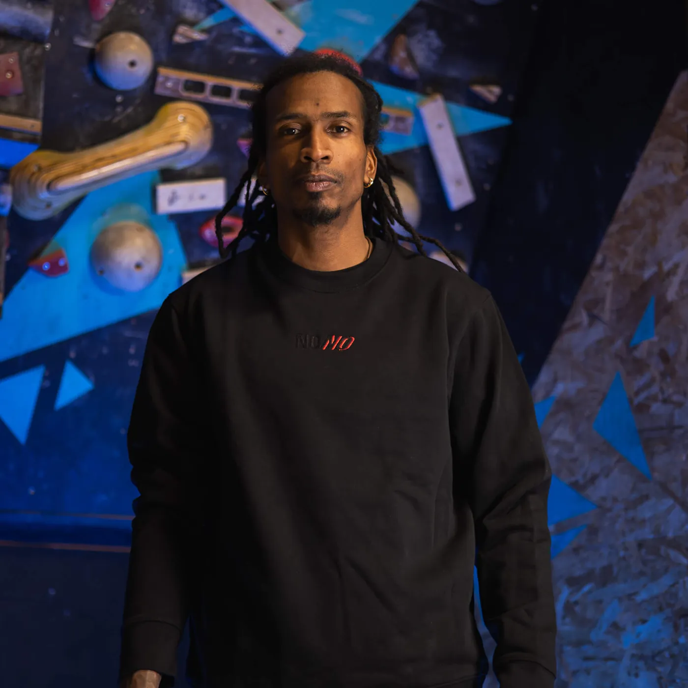 Man wearing the black NONO Signature crewneck in a climbing gym