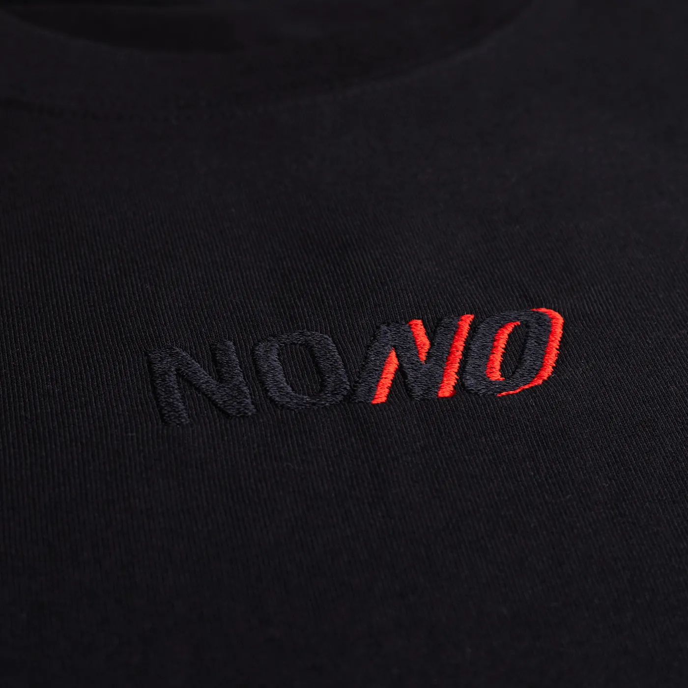Detail of the embroidered NONO logo on the t-shirt